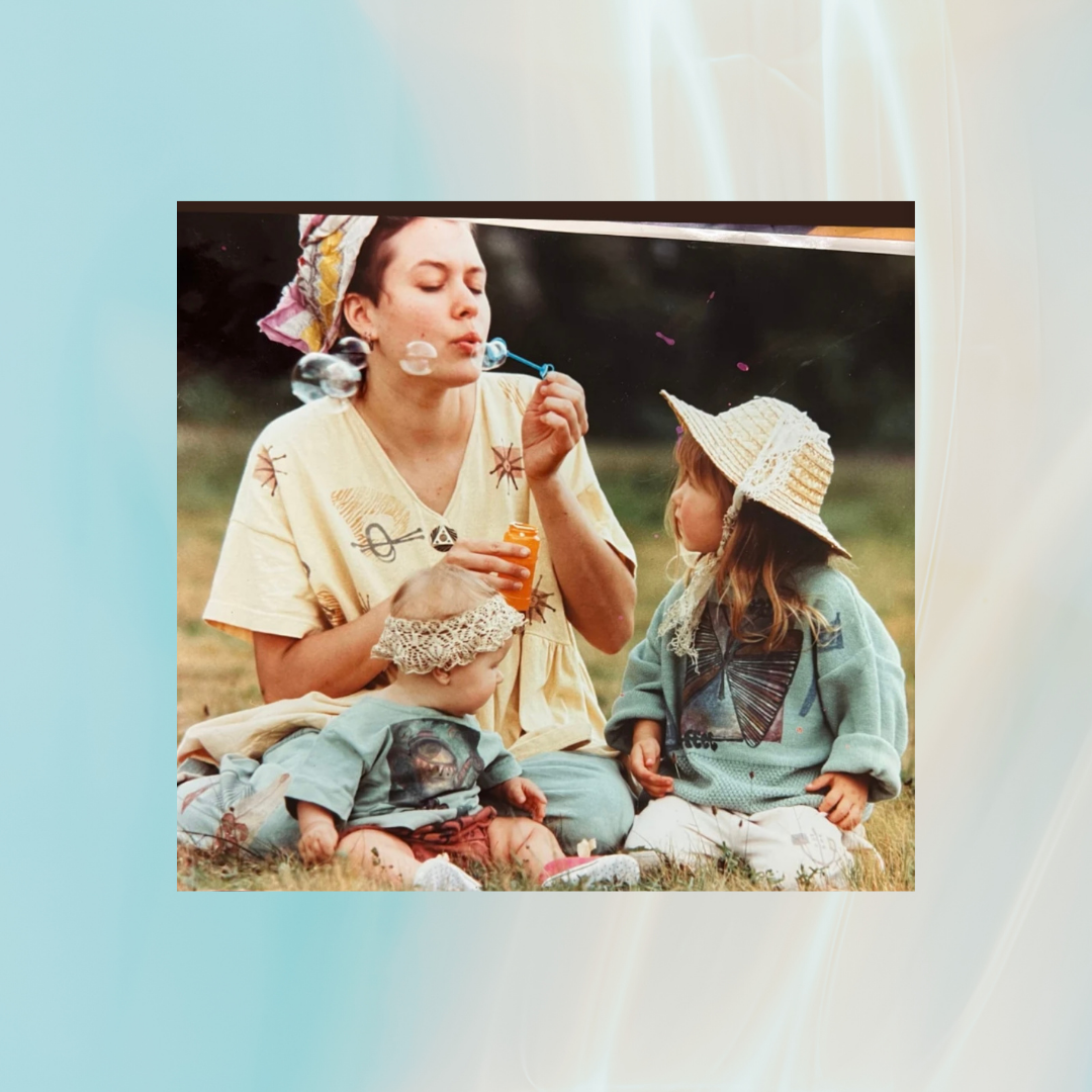 A woman blowing bubbles in a Yellow Tree top dress with two children, one wearing a hat, in a collection for children's Blue Fish from the Summer of 1995 only at Bluefishfinder.com.