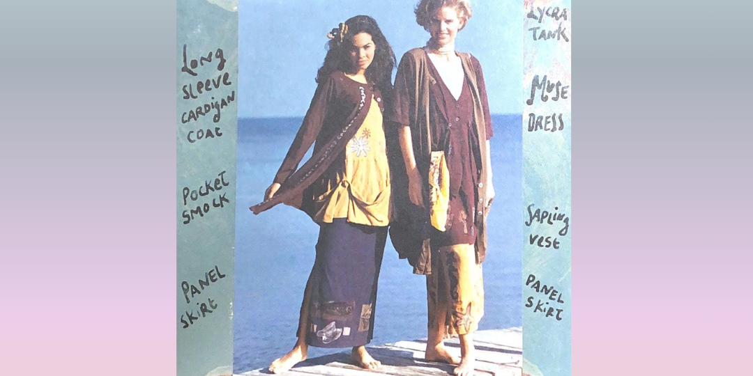 Two models sport the stronger colorway offered in the transitional collection from 1994. They stand on a skinny dock each wearing layers of Blue Fish Clothing. A few include: The elfin dress, straight skirt and pocket smock. Rounded clouds float above.