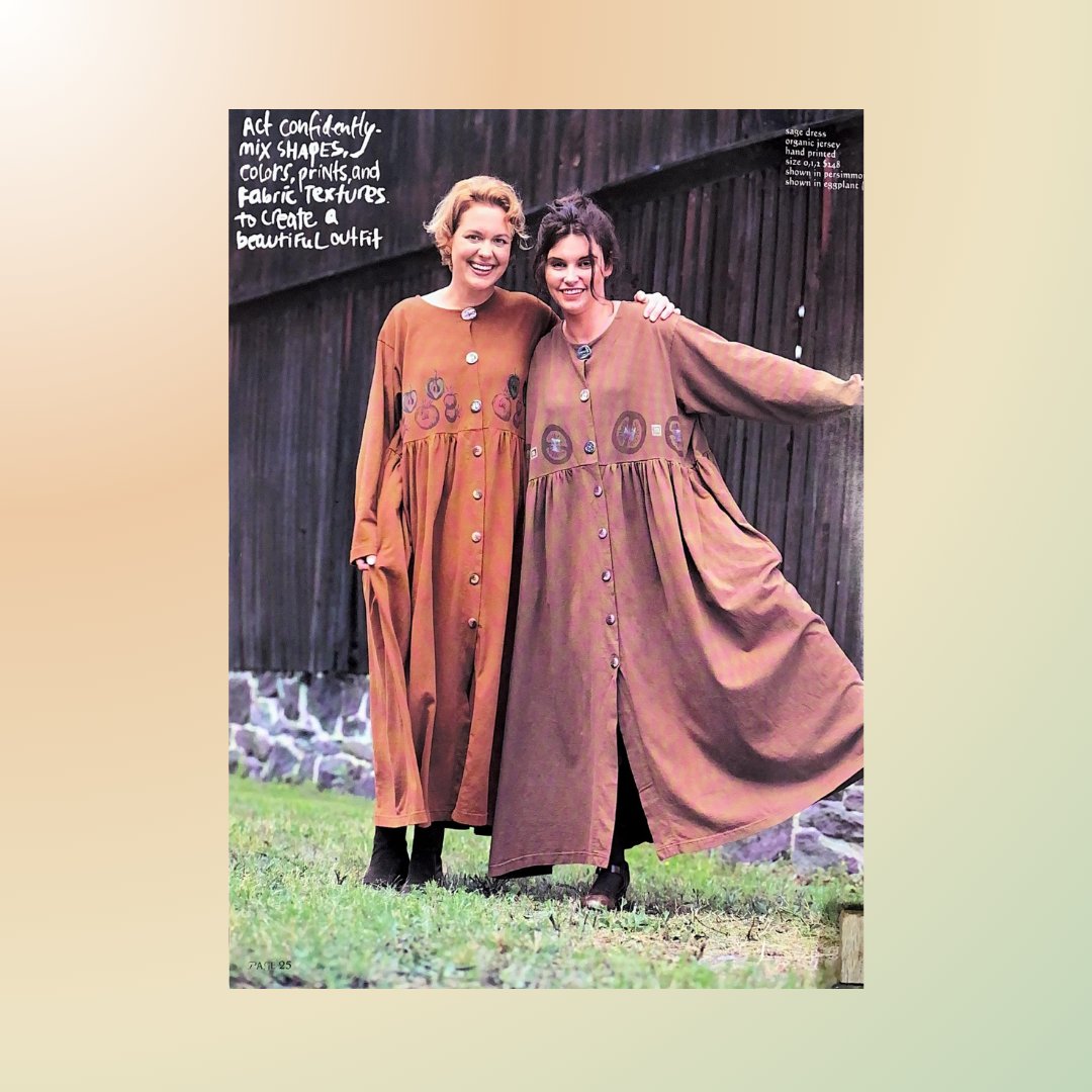 Twp Gals in full length dresses of harvest hues, wrap one arm to the other in celebration of beautiful clothing. They smiles widely and appear on a farm in front of a wooding barn. The grass is in the forefront and a stone foundation is in the background.