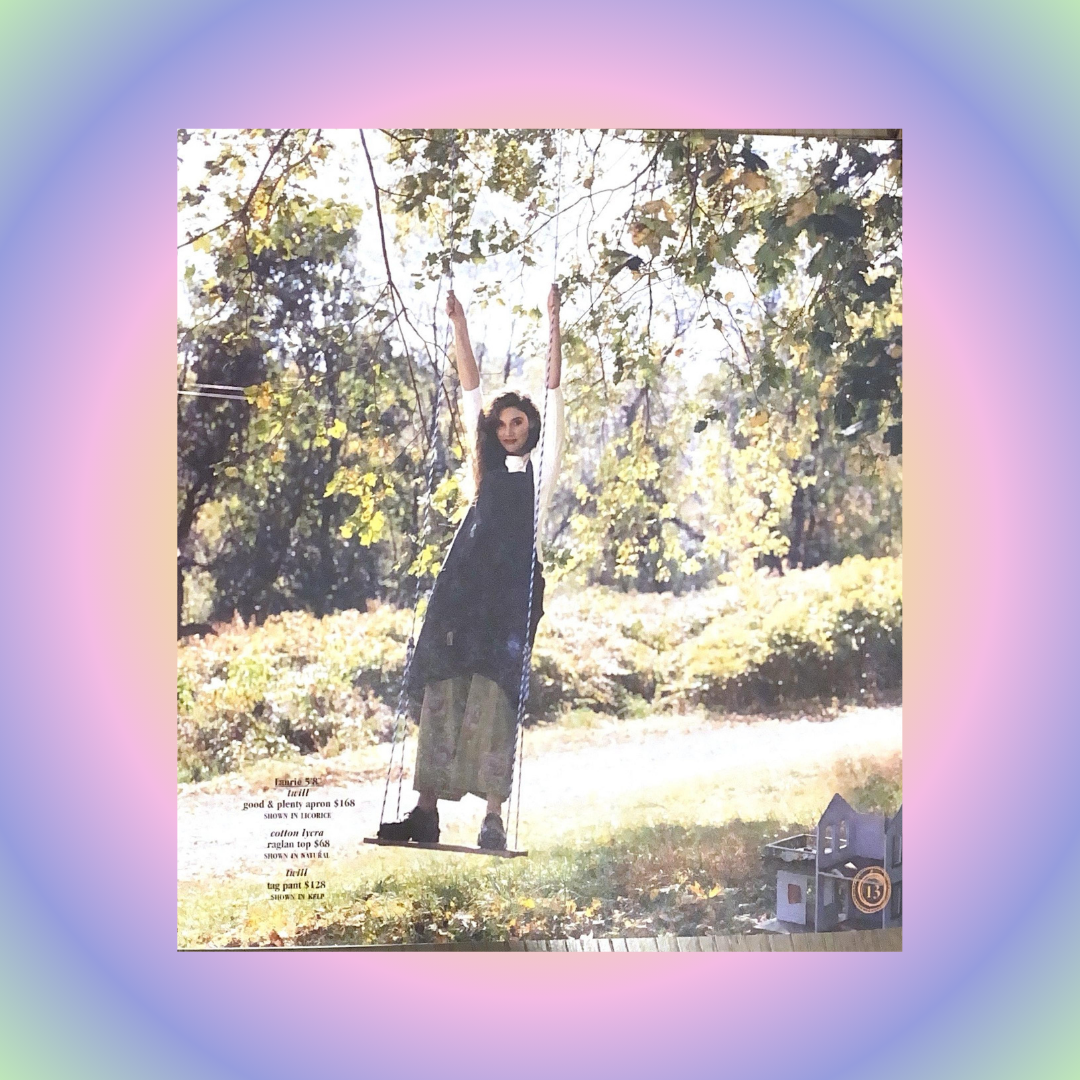 A young woman on a swing wears layered vintage Blue Fish clothing: a dark apron dress, raglan top, and patterned pants. Prices and Bluefishfinder logo are visible.