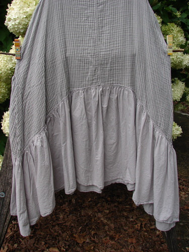 Barclay Gauze Batiste Summer Frock Jumper Stripe Light Stone Size 1, a loose gray striped frock with gauzy batiste texture and a soft gathered lower panel. The relaxed silhouette drapes over darker foliage, with muted light stone tones and a crinkled finish.