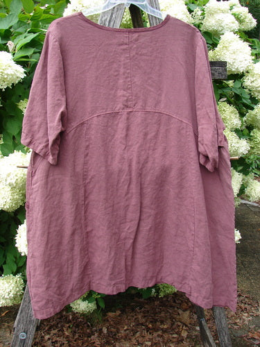 Barclay Summercloth Ditsy Trim Urchin Dress in unpainted loam, large size 0, shown as a loose mauve-brown dress with a round neckline, short sleeves, and a gently curved seam across the chest. The soft, wrinkled fabric hangs in a relaxed A-line shape against garden greenery and white blossoms.