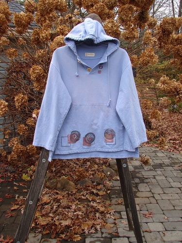 1999 Two Button Pullover Hooded Festive Moon Skylark Size L: A blue sweatshirt with a hood, featuring a festive moon theme and two front drop pockets.