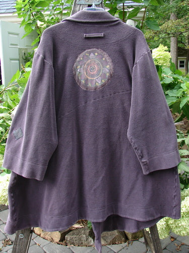 2000 PMU Celtic Moss Highlander Coat Aubergine Size 1 featuring oversized buttons, multiple patches, and a big collared front, displayed hanging with its unique design and heavy winter fabric.