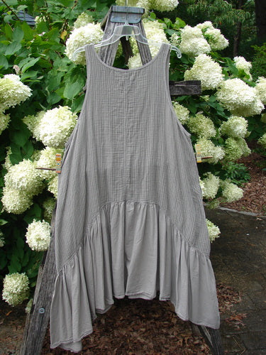 Barclay Gauze Batiste Summer Frock Jumper Stripe Sand Stone Size 1 in soft sand stone stripes, hanging from a wooden ladder. The sleeveless gauze batiste dress has a scoop neckline, a loose drape, and a gathered, tiered hem, set against white hydrangeas and dark foliage.