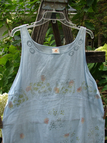 Barclay Batiste Short Tunic Tank Continuous Tiny Floral Birdsong Size 1 displayed on a clear plastic hanger against an outdoor backdrop, showcasing its rounded neckline, widening lower, and downward curved empire waist seam front.