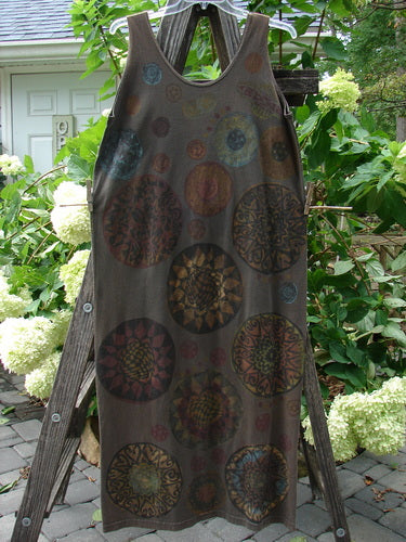 1992 Holiday Sleeveless Column Dress Giant Metallics Grey Sand OSFA displayed on a wooden ladder outdoors, featuring a scooped neckline, straight fall, and holiday-themed metallic pinwheel design.