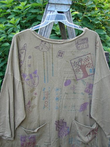 Barclay Cotton Hemp Rolled Writer's Pullover BF Kitty XOXO Mandorla OSFA displayed on a plastic hanger, featuring long sleeves, unique artistic drawings, rounded raw flutter neckline, and dual drop flop pockets.