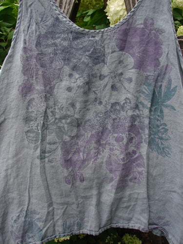 Barclay Linen Altoll Top Pansy Patch Blue Dust, a sleeveless linen top in muted blue-gray with a soft, washed texture and layered pansy print in gray, purple, and teal. The scoop neckline and gently frayed hem give it a relaxed, airy silhouette.