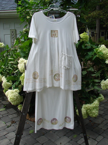 2000 NWT June Straight Duo Postage White Size 2: A white organic cotton dress with front pocket and matching straight skirt, both adorned with postage theme accents, displayed on a rack.