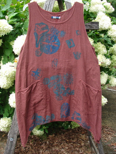 Barclay Summercloth Round Pocket Pinafore in rusty bucket size 0, a sleeveless rust-brown dress with a round neckline, curved front pockets, and a loose draped shape. Blue star and flower prints scatter across the soft, textured fabric.