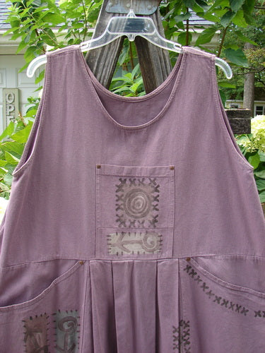 A purple 1995 Denim Invention Smock Modern Lolly Flower Heliotrope OSFA with front pleats, bib pocket, side pockets, and a wide A-line shape on a clothes hanger.