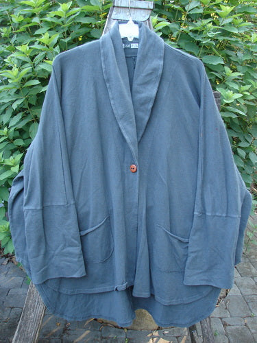 Barclay Reprocessed Golden Hour Deco Jacket Rear Rain Black Olive OSFA displayed on a wood post, highlighting the unique dense cotton texture, drop dolman shoulders, and deep V neckline with ribbed sleeves.