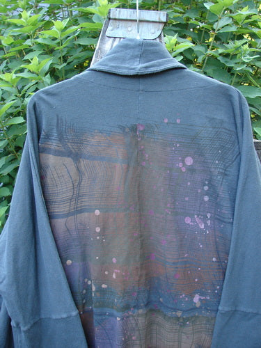 Barclay Reprocessed Golden Hour Deco Jacket in Black Olive, features dolman shoulders, a deep V-neckline, and diagonal oversized pockets. The jacket showcases a unique rear rain and grid paint theme.