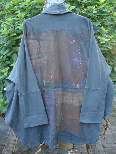 Barclay Reprocessed Golden Hour Deco Jacket Rear Rain Black Olive OSFA displayed on a swinger, highlighting its flowing varying lengths, drop dolman shoulders, and a distinctive deep V-shaped neckline with a stand-up collar.