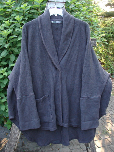 Barclay Patched Celtic Moss Deco Coat in Stormy Black, showcasing a thick cotton fleece texture with oversized vintage button, dolman shoulders, foldable sleeves, deep V neckline, and an oval-shaped hem.