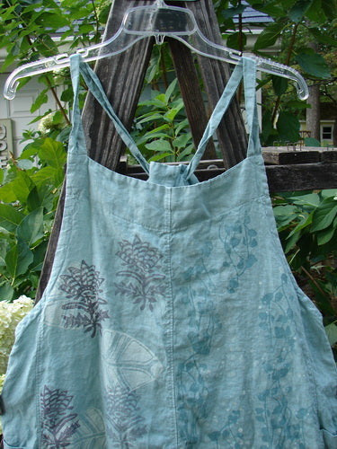 Barclay Linen Side Pocket Apron Jumper Fan Floral Dusty Sage Size 0 displayed on a wooden swing, showcasing sectional panels, adjustable shoulder straps, and two wrap side drop pockets.