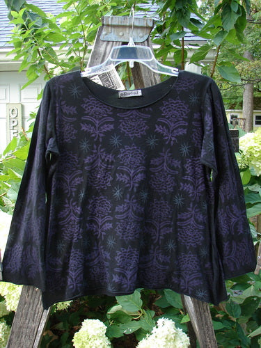 Barclay NWT Batiste Long Sleeved Pullover Fan Floral Black Size 0, featuring purple floral patterns, raw rolled edgings, and a gentle rounded neckline, displayed on a hanger.