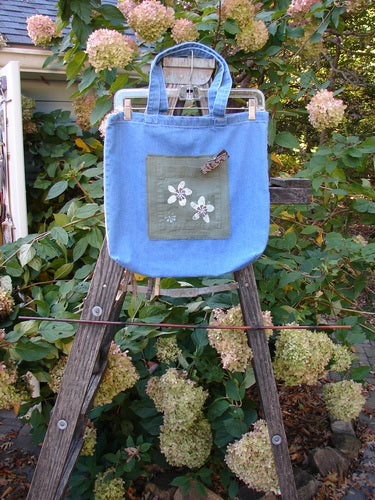 2000 PMU Cotton Tote Bag Summer Floral Pocket Washed Denim One Size displayed on a ladder, featuring floral patches, a center front pocket, and generous straps, celebrating sustainable vintage design from Bluefishfinder.com.