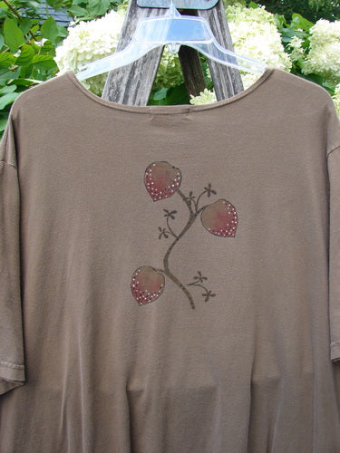 Barclay Short Sleeved Studio Tee Tree Offer Fauna Size 3 in muted taupe, a short-sleeved T-shirt with a soft matte knit and a centered tree-and-heart motif in dark and pink tones. It hangs on a clear hanger before leafy greenery and white blossoms.