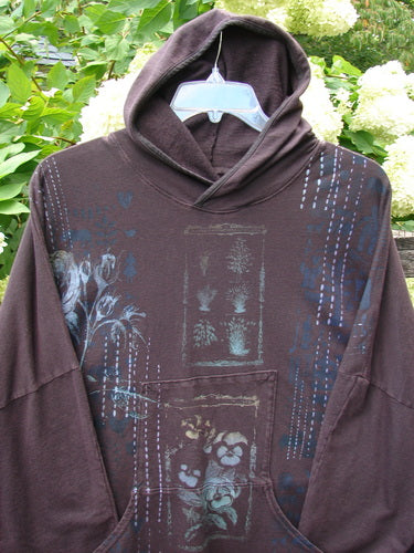 Barclay Cotton Lycra Dolman Roo Pocket Hoodie in Pansy Rose Deep Bark, with a draped hood, roomy dolman sleeves, and a centered roo pocket. The deep bark knit shows a soft, worn texture and layered blue floral-print details.