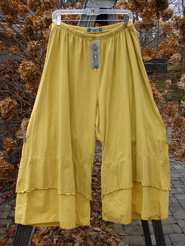 A close-up of Barclay NWT Crop Double Petal Pant, featuring a pair of yellow pants with double petal lower accents and slightly flared curly edges.