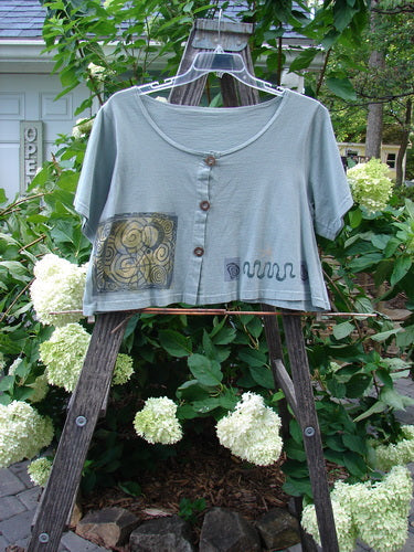 1993 Travel Top Many Moons Ocean Size 2 displayed on a clothesline, featuring a deeply scooped neckline, crop shape, and unique wooden buttons.