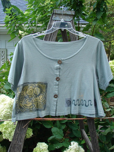 1993 Travel Top Many Moons Ocean Size 2 displayed on a hanger, featuring a deeply scooped neckline, cropped shape, rare wooden buttons, and a unique moons theme design.