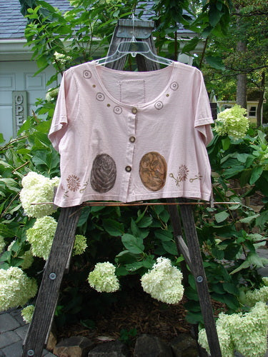 1993 Travel Top Oval Gardens Dried Rose Size 1: A pink shirt with brown designs, deeply scooped neckline, crop shape, button accents, and Blue Fish patch on the back, displayed outdoors.