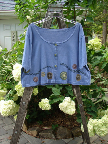 1993 Travel Top Pinwheel Periwinkle Size 2 displayed on a wooden ladder, showcasing a deeply scooped neckline and rare ceramic glazed buttons with a unique chain and pinwheel pattern.