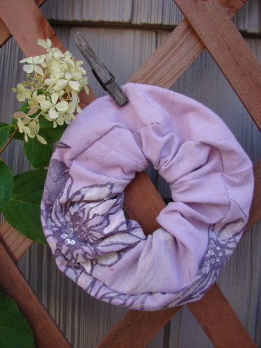 Barclay PMU Organic Cotton Hair Scrunchie Floral Lavender One Size, displayed on a wooden fence, features a ruffled fabric and floral theme, embodying Bluefishfinder.com's commitment to sustainable vintage designs.