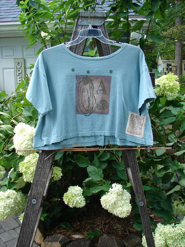 1994 Song Top Multi Letter K Ice Size 1 displayed on a wooden ladder, featuring a wide boxy shape, shallow neckline, vintage buttons, and an oversized painted breast pocket.