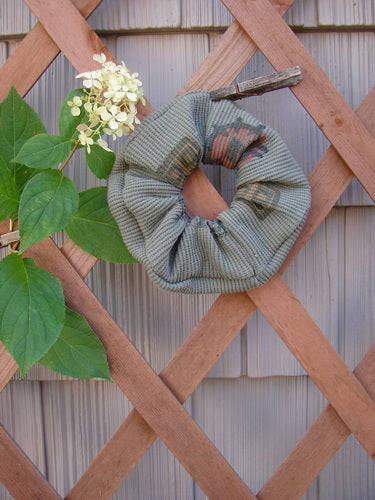 1995 PMU Thermal Hair Scrunchie Abstract Greenwear One Size on a wooden lattice, showcasing a ruffled fabric with a thin elastic interior band, highlighting its vintage, sustainable design from Bluefishfinder.com.