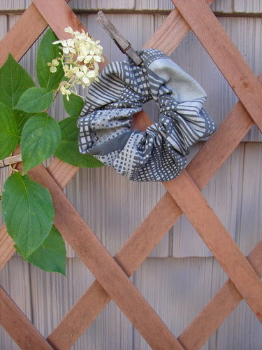 Barclay PMU Cotton Lycra Hair Scrunchie Graphics Grey Black One Size, displayed on a fence, features a ruffled fabric with a thin elastic band, showcasing sustainable vintage design.