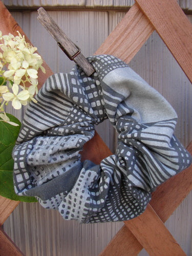 Barclay PMU Cotton Lycra Hair Scrunchie Graphics Grey Black One Size displayed on a wooden fence, showcasing its ruffled fabric and elastic band, embodying sustainable vintage-inspired design by Bluefishfinder.com.