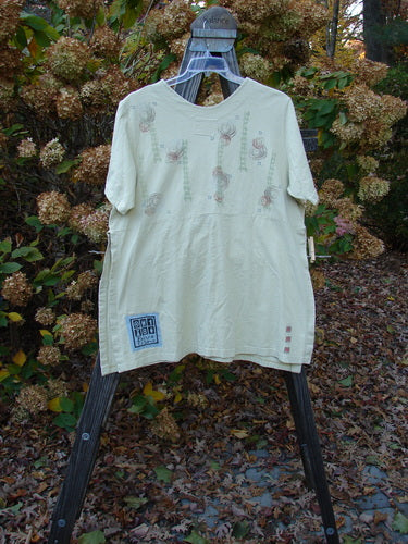 A white Barclay Short Sleeved Pocket Vent Tunic with a unique reverse triangular neckline insert, short sleeves, and tall side vents. It features two drop exterior pockets and a celebrate theme paint design. Made from organic cotton, this size 0 tunic is in perfect condition.