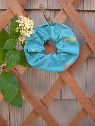 1990 PMU Cotton Hair Scrunchie Abstract Turq One Size displayed outdoors, showcasing its ruffled cotton fabric with abstract paint design, emphasizing its vintage-inspired, recycled style from Bluefishfinder.com.