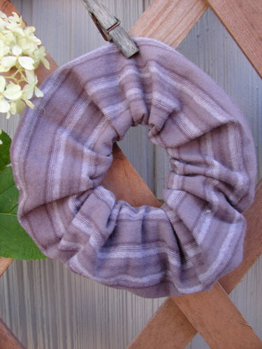 1999 PMU Organic Cotton Hair Scrunchie Unpainted Grey Plum Stripe One Size displayed on a wooden fence, showcasing its ruffled fabric and elastic band, highlighting sustainable design from the Bluefishfinder collection.