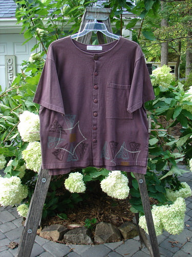 1998 Camp Shirt Triangular Star Madeira Size 1 displayed on a wooden swing, showcasing its unique features like the oversized front pocket, vented hemline, and original buttons, with slight fade on the shoulder seam.