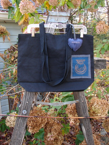 1998 PMU Patched Tote Bag Sling Sun & Wind Black One Size displayed on a ladder, featuring extra-long shoulder straps, a generous top opening, a gusseted bottom, and a colorful puffy heart accent.