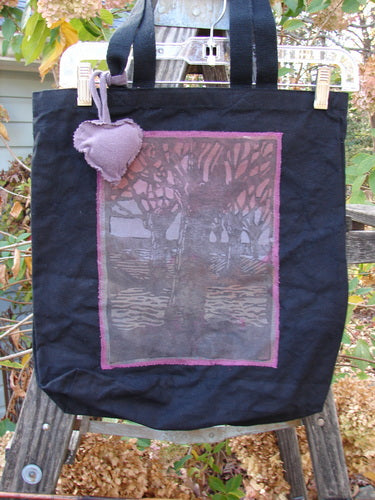 1994 PMU Patched Tote Bag Forest Walk Black One Size, featuring a distinctive purple heart patch on heavy black canvas, displayed on a wooden ladder, highlighting its sustainable vintage design and extra-long shoulder straps.