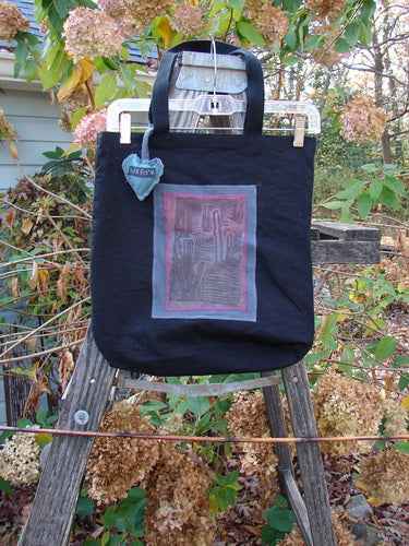 1994 PMU Patched Tote Bag Wood Path Black One Size displayed on a ladder, features a colorful puffy heart accent, extra-long shoulder straps, and a generous top opening, embodying sustainable vintage design.