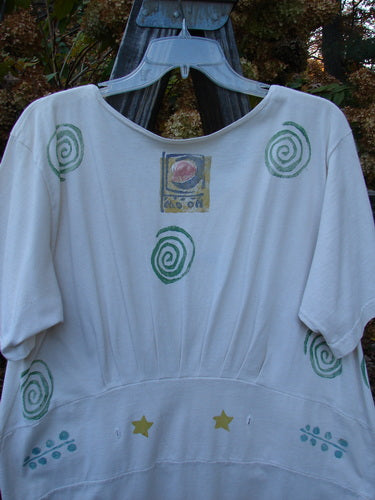 1992 Little Storma Dress Moon White OSFA: A white shirt with green spirals and stars on it. Features a logo and a green spiral.