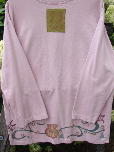 1993 Long Sleeved Tee Ocean Folly Ask Pink OSFA in soft pink cotton, shown with a loose long-sleeve cut, a small olive chest patch, and a flowing multicolor vine-and-shell graphic along the hem.