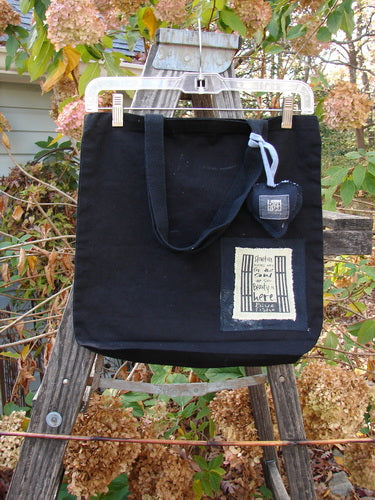 2000 PMU Patched Tote Bag Geos Black One Size features a colorful puffy heart patch, displayed on a wooden ladder. It boasts extra-long straps and a gusset bottom for vintage-inspired sustainability.