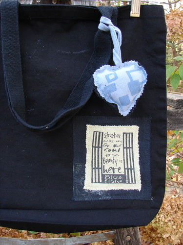 2000 PMU Patched Tote Bag Geos Black One Size features a blue heart patch on heavy black canvas, showcasing extra-long shoulder straps, a gusset bottom, and a generous top opening.