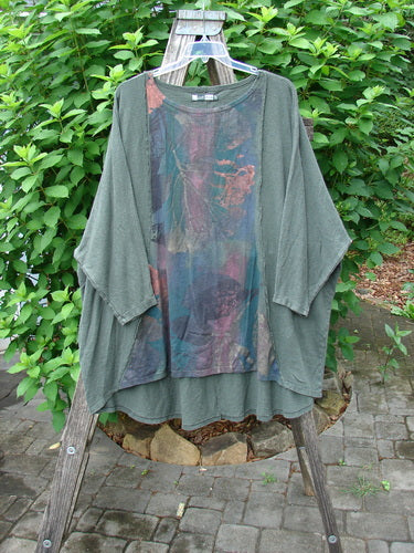 Barclay Cotton Hemp Exterior Stitch Hi Low Tunic Metallic Floral Green Stick OSFA displayed on a chair, highlighting its dolman sleeves, curvy seams, and distinctive high-low hemline in cozy fall fabric.