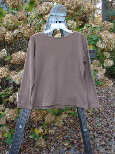1997 PMU Patched Thermal Long Sleeved Top Leaf Mandorla Size 1: A brown shirt on a wooden rack, featuring a leaf patch and whip stitchery border.