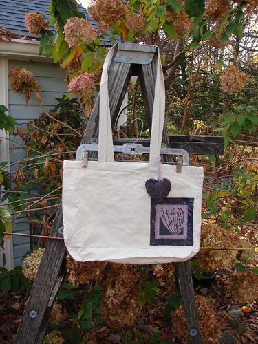 1995 PMU Patched Tote Bag Sling Vintage Logo Frayed Natural Lilac One Size displayed on a wooden ladder, showcasing its colorful puffy heart accent, long shoulder straps, and signature patch.