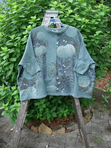 Barclay Fleece Banded Sleeve Colors Sweatshirt Moon Flower Olive Drab OSFA displayed outdoors on a hanger, showcasing its wide boxy shape and unique moon flower design on heavyweight organic cotton fleece.